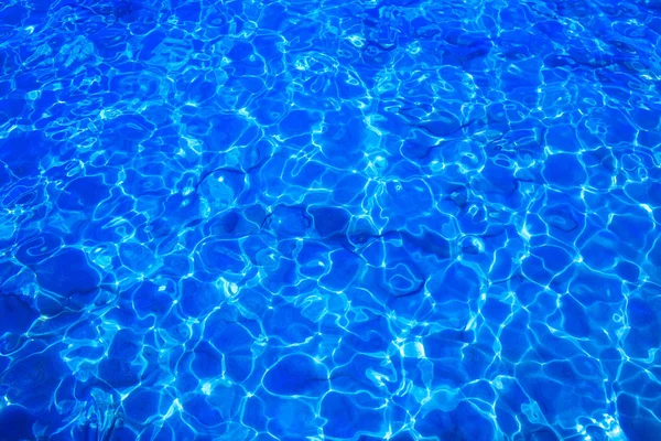 Água clara azul com superfície ondulada e fundo de areia . — Fotografia de Stock