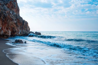 Kumlu plaj ve beyaz köpük ile yumuşak mavi okyanus dalgası.