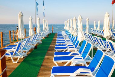 Sahil iskelesinde birçok mavi şezlong.