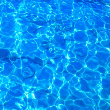 Dalgalı yüzey ve kum alt ile mavi berrak su.