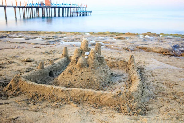 Castelo de areia na praia de areia da manhã . — Fotografia de Stock