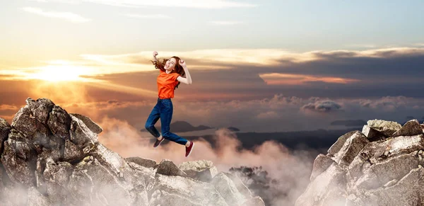 Redhead woman jumps over cliff on blue sky background. — Stock Photo, Image