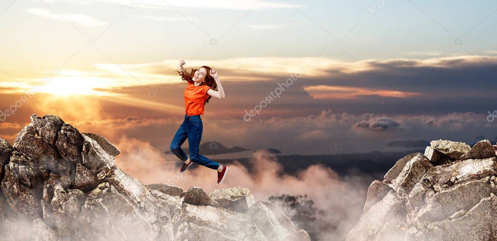 Redhead woman jumps over cliff on blue sky background.