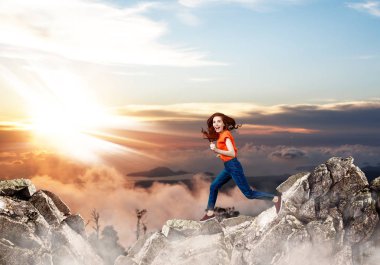 Kızıl saçlı kadın mavi gökyüzü arka planda uçurumun üzerinde atlar.