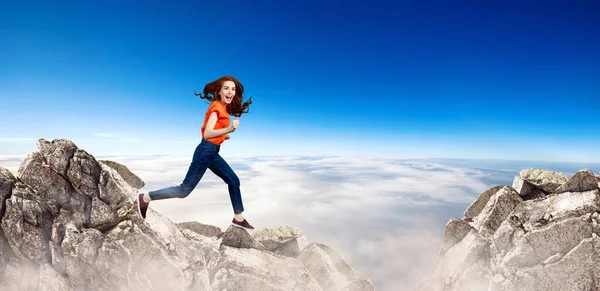 Redhead woman jumps over cliff on blue sky background. — Stock Photo, Image