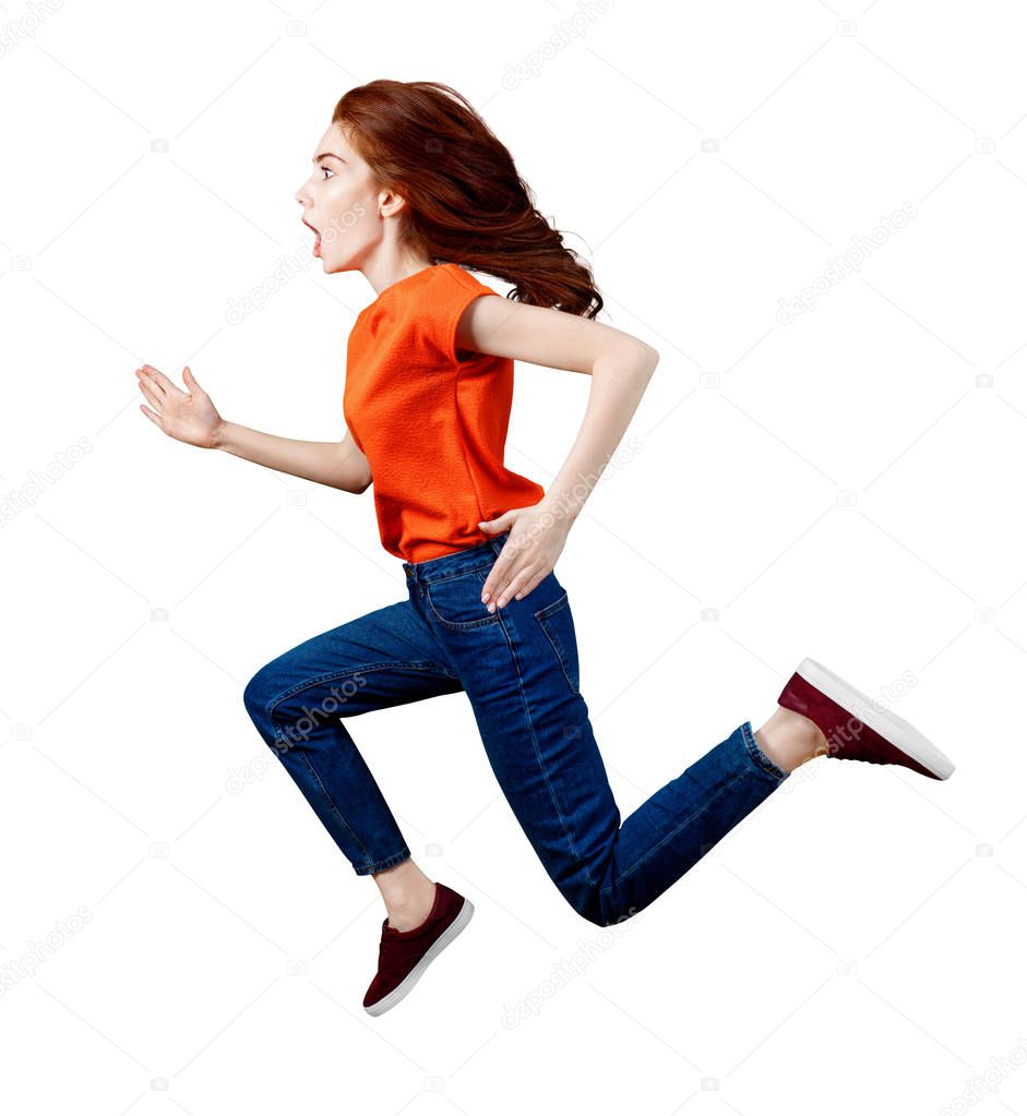 Full length happy ginger woman in shirt and jeans jumping.