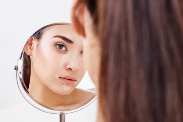 Mujer con ojos magullados mira su reflejo en el espejo . —  Fotos de Stock