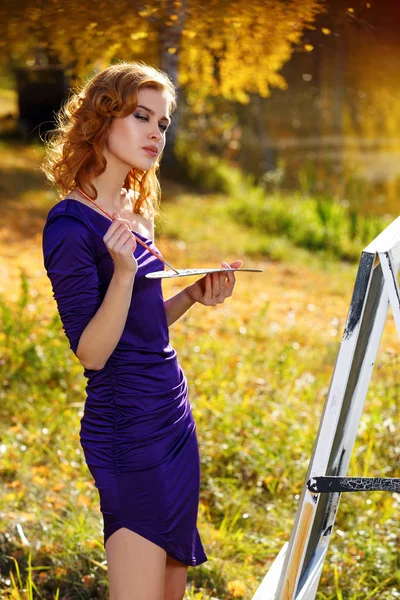 Jeune femme en robe sexy peinture en plein air dans le parc d'automne . — Photo