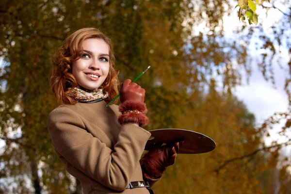 Mujer joven posando con paleta y cepillo al aire libre en el parque de otoño . — Foto de Stock