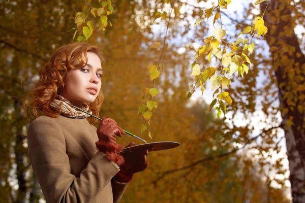 Mujer joven posando con paleta y cepillo al aire libre en el parque de otoño . — Foto de Stock