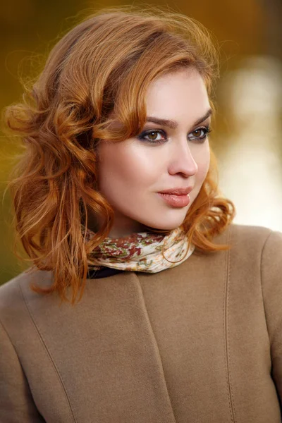 Stylish woman in beige coat and gloves standing in autumn yellow park. — Stock Photo, Image