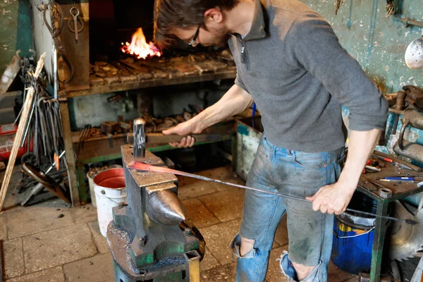 Herrero forjando metal rojo-caliente con martillo . — Foto de Stock