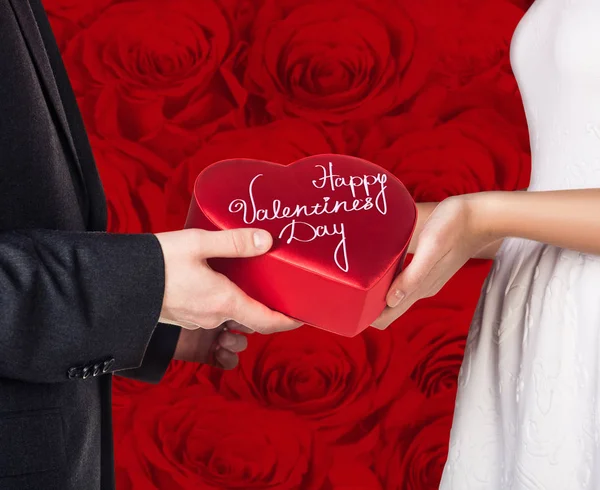 Close-up hands of young couple with red heart shaped gift box. — Stock Photo, Image