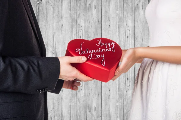 Close-up hands of young couple with red heart shaped gift box. — Stock Photo, Image