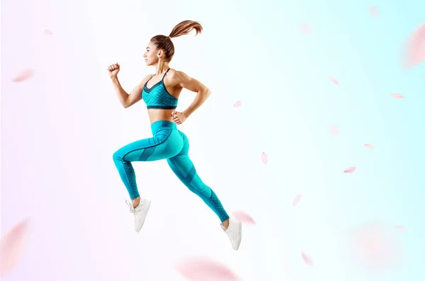 Młoda kobieta biegacz w niebieskim strój sportowy skok w powietrzu. — Zdjęcie stockowe