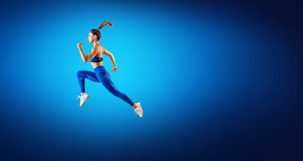 Jonge vrouw runner in blauwe sportwear sprong in de lucht. — Stockfoto
