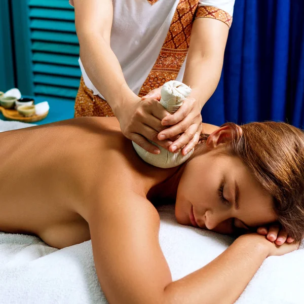 Kvinna får massage med heta växtbaserade väskor. — Stockfoto