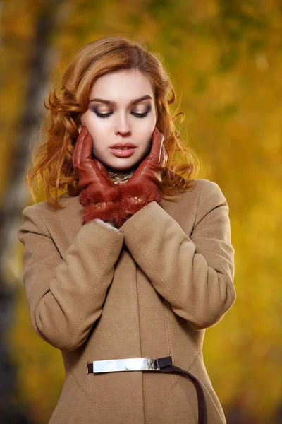 Mujer con estilo en abrigo beige y guantes de pie en el parque amarillo de otoño . — Foto de Stock