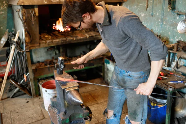 Herrero forjando metal rojo-caliente con martillo . — Foto de Stock