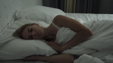 Genç kadın rahat rahat taze yatakta uyanış ve akıllı telefon alır.