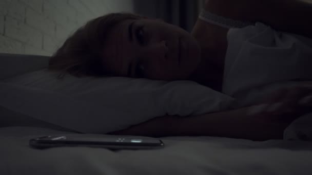 Schläfrige Frau schaltet Wecker beim Aufwachen am Morgen aus. — Stockvideo