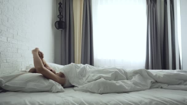 Женщина просыпается в удобной уютной кровати растягиваясь и встает . — стоковое видео