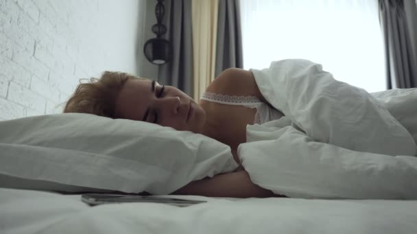 Mujer somnolienta apaga la alarma mientras se despierta por la mañana . — Vídeos de Stock