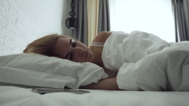 Mulher sonolenta desliga o alarme enquanto acorda de manhã . — Vídeo de Stock