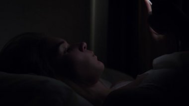 Gece uyumadan önce yatakta akıllı telefon kullanan kadın.