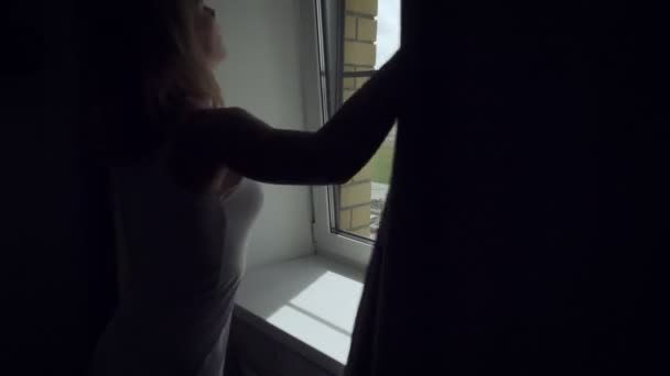 Mladá žena otevřené záclony časně ráno. — Stock video