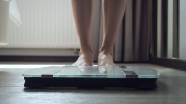 Nierozpoznawalna kobieta stoi na skali podłogi w sypialni. — Wideo stockowe