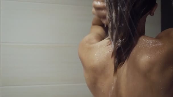 美しい女の子は髪を洗い、シャワーの下で自分自身を楽しむ. — ストック動画