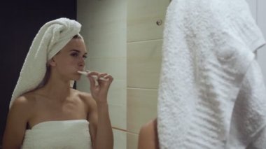 Güzel kadın dişlerini fırçalıyor ve aynaya bakıyor..
