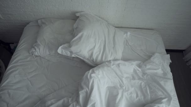 Unaufgeräumtes zerknülltes Bett mit weißer Bettwäsche. — Stockvideo