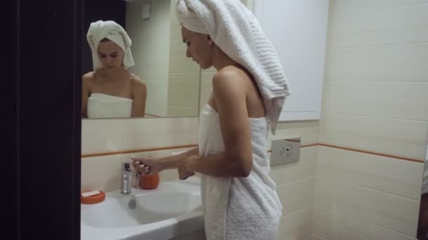 Jonge vrouw het wassen van haar gezicht in de badkamer. — Stockvideo
