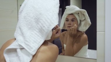 Banyoda kirpiklere maskara uygulayan genç kadın.