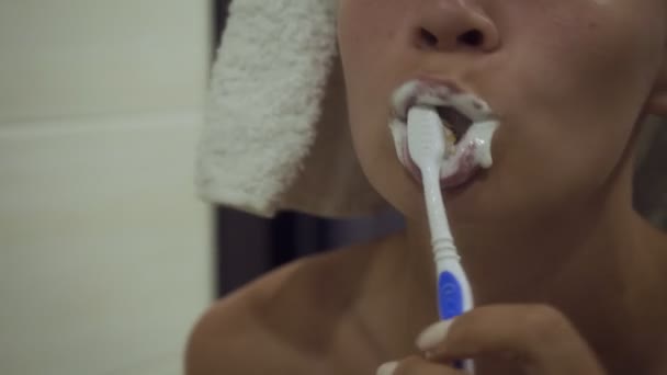Dişlerini fırçalayan ve aynaya bakan kadının yakın çekim fotoğrafı. — Stok video