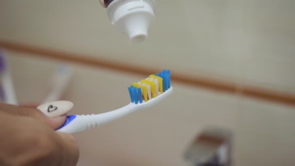 Närbild skott av kvinnliga händer klämma tandkräm på borsten. — Stockvideo