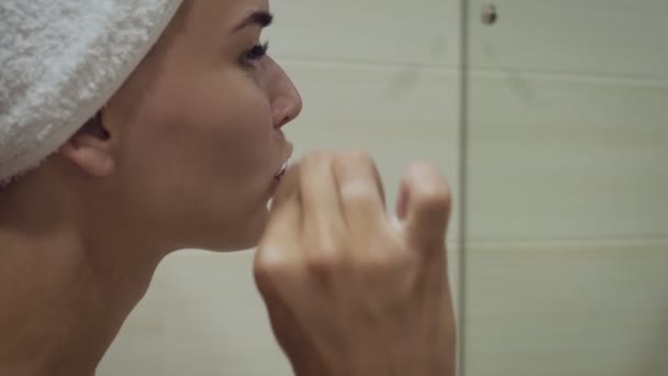 Primer plano de la mujer cepillándose los dientes y mirándose en el espejo . — Vídeos de Stock