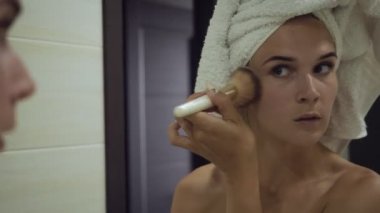 Genç kadın banyoda büyük fırça ile toz uygulayarak.