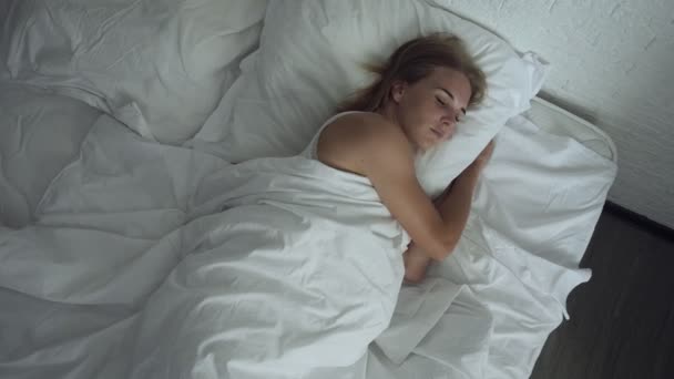 Женщина просыпается в удобной уютной кровати растягиваясь и встает . — стоковое видео