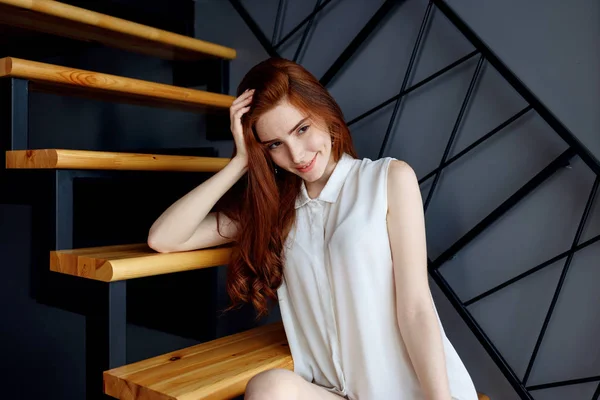 Redhead kvinna sitter på trappan i loft lägenhet. — Stockfoto