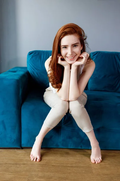 Redhead woman sitting on the blue couch at home. — Stock Photo, Image