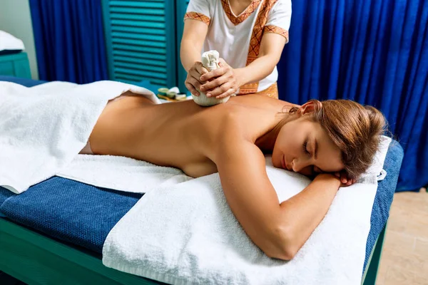Woman getting massage with hot herbal bags. — Stock Photo, Image