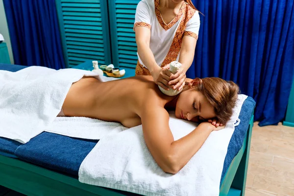 Vrouw krijgt massage met hete kruiden tassen. — Stockfoto