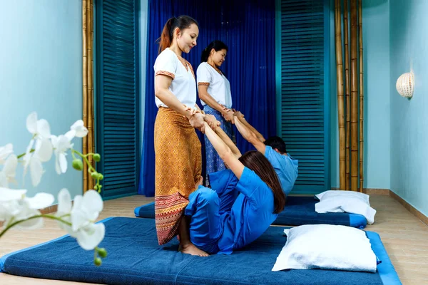 Dwie tajskie masażystów synchronicznie robi masaż tajski. — Zdjęcie stockowe
