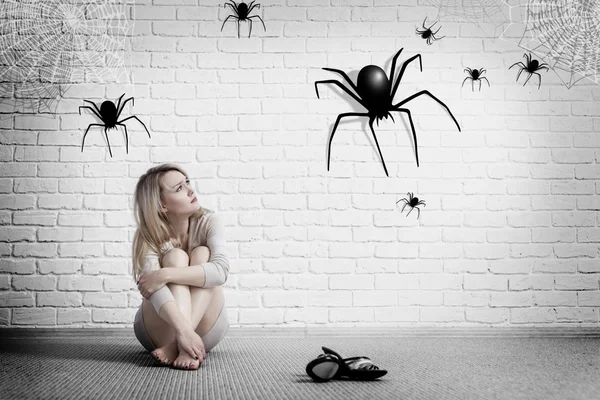 Kvinna sitter på golvet och tittar på imaginär spindel. — Stockfoto