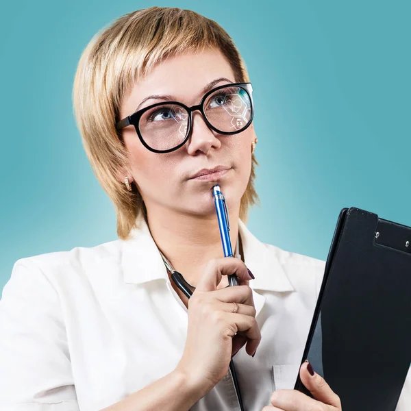 Thoughtful doctor woman holds clipboard and looking up. — Stock Photo, Image