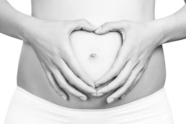 Mujer embarazada sosteniendo sus manos en forma de corazón en el vientre . — Foto de Stock