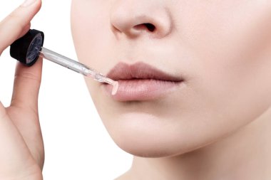 Genç kadın dudaklarına nemlendirici merhem uyguluyor.